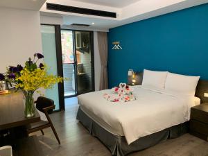 1 dormitorio con 1 cama grande y pared azul en Greenight Hotel, en Taichung