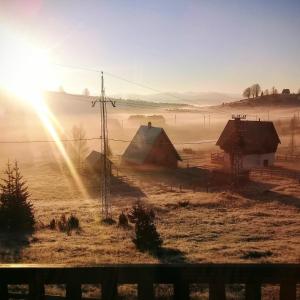 a foggy field with a barn and the sun shining at Chalet Kovačević in Žabljak