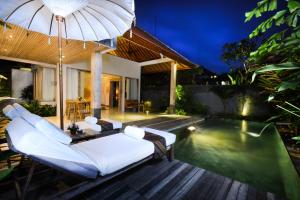 an outdoor patio with a pool and an umbrella at Purana Boutique Resort in Ubud