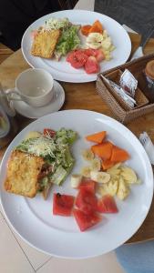 two plates of food on a table with fruits and vegetables at Undis Homestay in Ubud