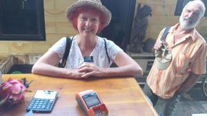 a woman sitting at a table with a cell phone at Undis Homestay in Ubud