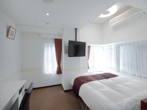 京都市にあるチェックイン四条烏丸のベッド1台、薄型テレビが備わるホテルルームです。