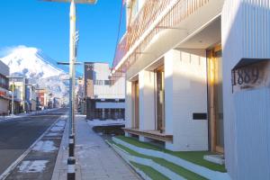 a street with a building and a snow covered mountain at Hostel 1889 in Fujiyoshida