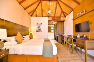 a bedroom with a large bed and a dining room at Plumeria Maldives in Thinadhoo