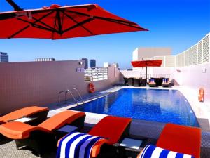 a pool on the roof of a building with chairs and an umbrella at Landmark Grand Hotel in Dubai