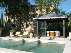 a swimming pool with a gazebo next to a house at Hotel du Poète in Fontaine-de-Vaucluse