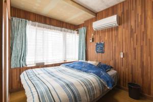 1 dormitorio con 1 cama, ventana y ventilador en NahaCentaral_10Beds7roomsHouse_190sqm_FreeParking, en Naha