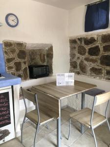 a table with two chairs and a clock on the wall at Bouganville- Le casette di Marilena in Pantelleria