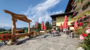 un patio con mesas, sillas y sombrillas rojas en Almfrieden Hotel & Romantikchalet en Ramsau am Dachstein