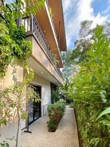 a walkway leading to the side of a building with plants at Pensiri House - SHA Extra Plus in Nai Yang Beach