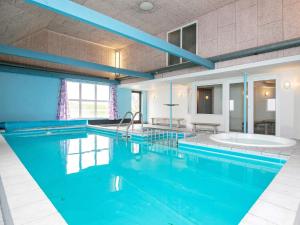 een groot zwembad met blauw water in een gebouw bij 14 person holiday home in L gst r in Løgstør
