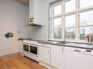 een keuken met witte kasten, een wastafel en ramen bij Holiday Home Åstedvej in Åsted