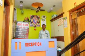 um homem atrás de um balcão de recepção num quarto em Hotel Sai Darshan em Shirdi