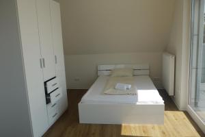 a small white bedroom with a bed and a window at Vermietung Flaßkamp in Harsewinkel