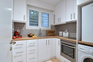 cocina blanca con armarios blancos y ventana en Acropolis, a nice and minimal apartment en Atenas