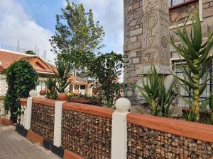 a fence in front of a building with plants at Achill Houses in Thika