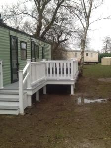 a house with a white porch and a white bench at 19 Laurel Close Highly recommended 6 berth holiday home with hot tub in prime location in Tattershall