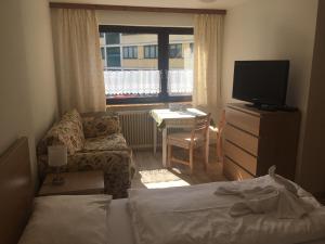 ein Schlafzimmer mit einem Bett, einem TV und einem Stuhl in der Unterkunft Alpenpension Haslinger in Bad Gastein