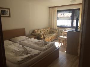 ein Schlafzimmer mit einem Bett und einem Sofa sowie ein Wohnzimmer in der Unterkunft Alpenpension Haslinger in Bad Gastein