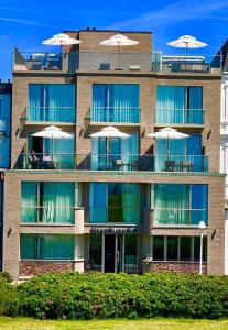 a building with tables and umbrellas on the balcony at MeerBlickD21 in Norderney