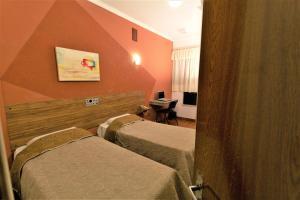 ein Hotelzimmer mit 2 Betten und einem Schreibtisch in der Unterkunft Hotel Pouso Novo in Matão