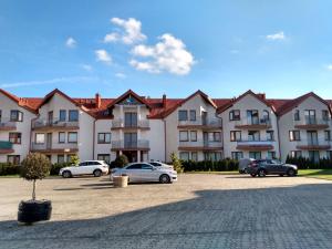 a large apartment building with cars parked in a parking lot at Złoty Piasek in Darłowo