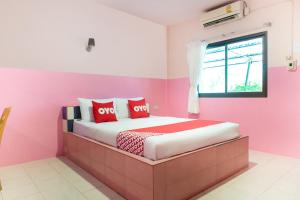 una camera da letto con pareti rosa e un letto con cuscini rossi di OYO 627 Sai Thai Garden Home Travel ad Aonang Beach