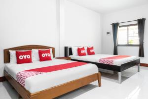 2 letti in una camera con cuscini rossi e bianchi di OYO 627 Sai Thai Garden Home Travel ad Aonang Beach