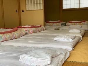 a row of white beds lined up in a room at Yasunoya #HH2x in Toyama