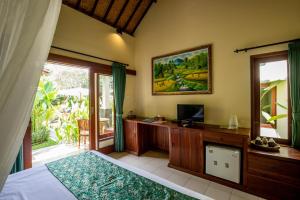 um quarto com uma cama e uma secretária com uma televisão em Sisin Ubud View em Ubud