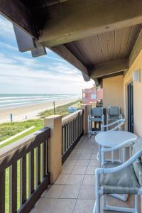 a balcony with a table and chairs and the beach at Tiki 332 in South Padre Island