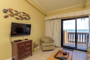 a living room with a television and a chair at Tiki 332 in South Padre Island
