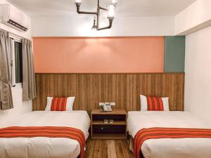 una camera d'albergo con due letti e una parete arancione di 金銀花民宿 a Ji'an