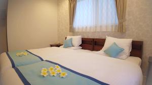 una habitación de hotel con 2 camas con flores. en Ecot Shimozato 1, en Isla Miyako