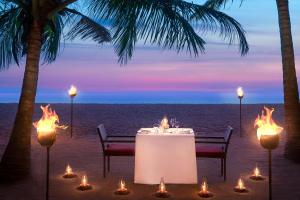 a table with candles on the beach with the ocean at Avani Kalutara Resort in Kalutara