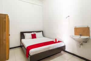 RedDoorz near Widya Mandala University في سورابايا: غرفة نوم صغيرة بها سرير ومغسلة
