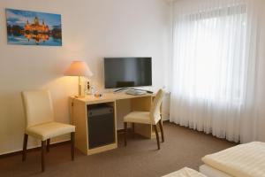 a hotel room with a desk with a television and chairs at Hotel Bertram in Schwarmstedt