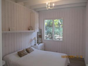 a bedroom with a white bed and a window at une maison lumineuse sous les pins in Le Canon