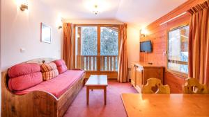 a living room with a couch and a tv at Vacancéole - Résidence Les Chalets de la Ramoure in Valfréjus