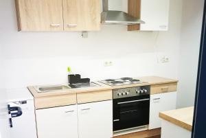 a kitchen with white cabinets and a stove and a sink at Work & Stay in Emmerich in Emmerich