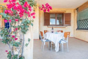 a table and chairs in a room with pink flowers at Sardegna Pittulongu Villetta vista mare in Olbia