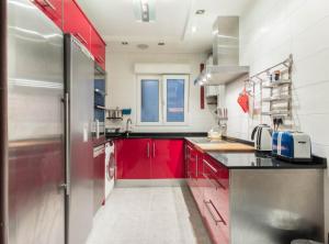 a kitchen with red cabinets and a refrigerator at Casa txema tu casa en Bilbao by Urban Hosts in Bilbao