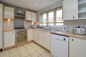 a kitchen with white cabinets and white appliances at Luxury Boutique House - Close to MK City Center in Milton Keynes