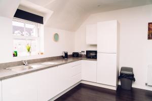 a white kitchen with a sink and a window at Detached Coach House in Colchester