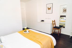 a white bedroom with a bed and a chair at Detached Coach House in Colchester