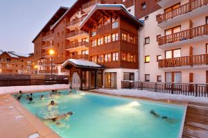 a group of people in a swimming pool in a building at Vacancéole - Résidence Les Chalets de la Ramoure in Valfréjus