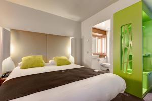 ein Schlafzimmer mit einem großen Bett mit grünen Akzenten in der Unterkunft Campanile La Roche Sur Yon Centre Gare in La Roche-sur-Yon