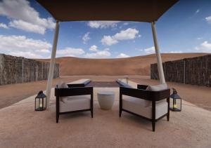 two chairs sitting under an umbrella in the desert at Mysk Al Badayer Retreat in Sharjah