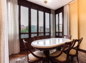 a dining room with a table and chairs and windows at Piso Señorial con vistas a la ria by Urban Hosts in Bilbao