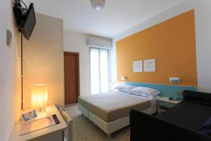 um pequeno quarto com uma cama e uma televisão em Mini Hotel em Rimini